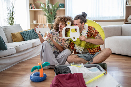 Young couple planning summer vacation with car and campervan cardboard icons