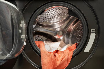 Dirty wet towels in front load washing machine drum interior close up showing laundry and cleaning...