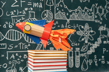 Paper rocket on stack of books with chalkboard background science education creativity learning...