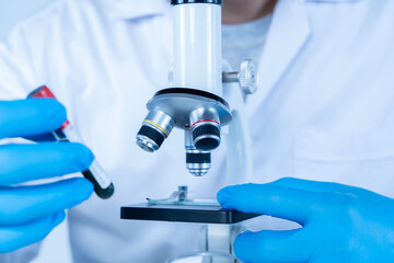Scientist analyzing blood sample under microscope in laboratory, medical research and diagnostic...