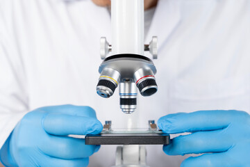 Scientist hands with gloves adjusting microscope slide in laboratory close up for science research...