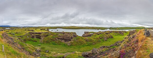 Lava formations and lake in Myvatn Iceland under cloudy sky