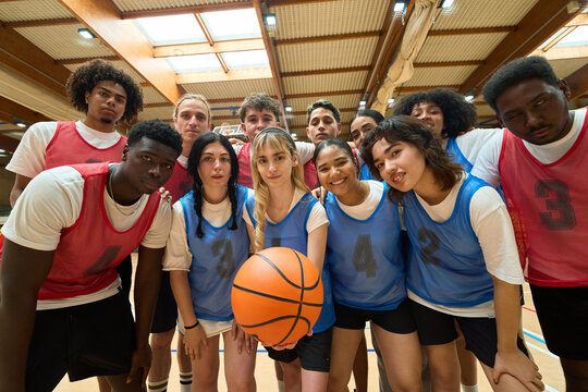 High school basketball team posing with ball in gymnasium - Powered by Adobe