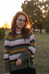Portrait of a young beautiful cheerful red-haired girl in an evening autumn city.
