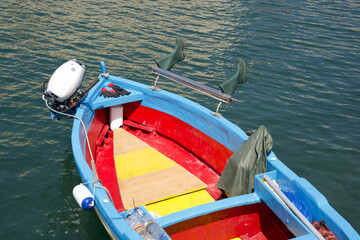 Obraz premium Colorful fishing boat with blue and red paint floating on calm water in a serene coastal environment