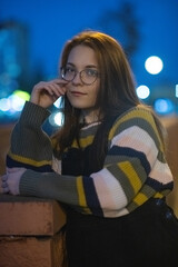 Portrait of a young beautiful cheerful red-haired girl in an evening autumn city.