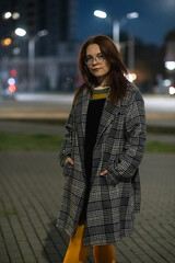 Portrait of a young beautiful cheerful red-haired girl in an evening autumn city.