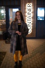 Portrait of a young beautiful cheerful red-haired girl in an evening autumn city.