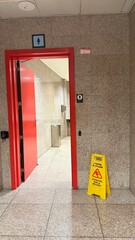 Barcelona, Spain - March 31, 2025: Restroom entrance with red door, caution sign, and modern design...
