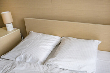 Two white comfortable pillows on the bed in the interior of a hotel room
