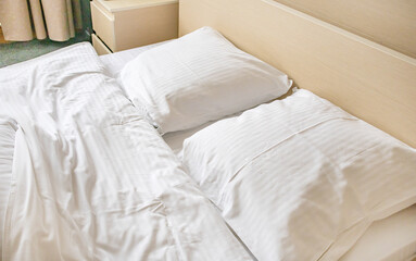 Two white comfortable pillows on the bed in the interior of a hotel room