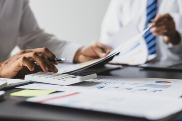 Businessman is calculating profit and analyzing financial data on report in office. Advisor is...