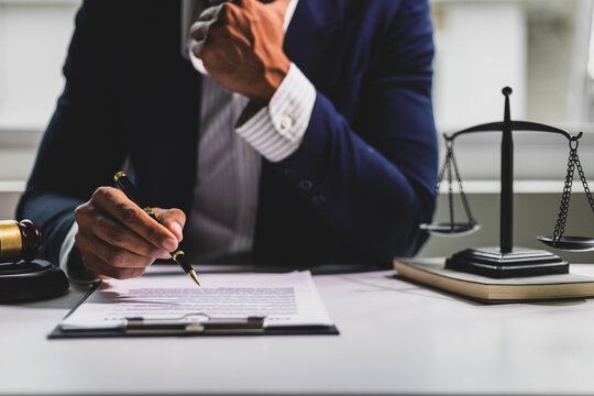 Lawyer reading legal documents and preparing to sign a contract. Lawyer is carefully reviewing legal documents at his desk.
