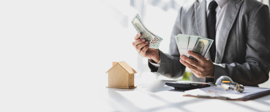 Businessman holding banknotes and counting money, savings, rent, cash flow, accounting, real estate. Real estate agent businessman counting cash, deposit or commission on real estate sales.