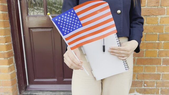Woman with USA flag and notebook, concept of immigration, study, and dreams.
