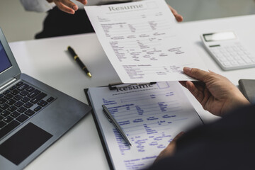 Employer reviewing resume during job interview in office. Human resources manager reading...