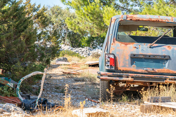 Rear shot of a heavily corroded SUV with broken windows, surrounded by scattered construction...