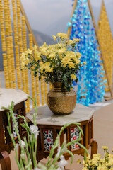 Floral Arrangement on Marble Table: Yellow daisies and baby's breath in a brass vase, decorative...