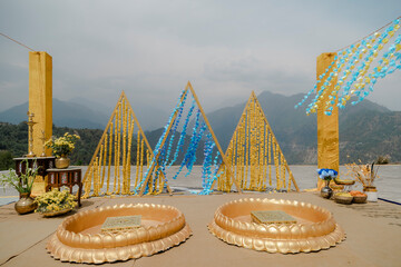 Outdoor event setup with triangle structures decorated with blue and yellow flower garlands and two...