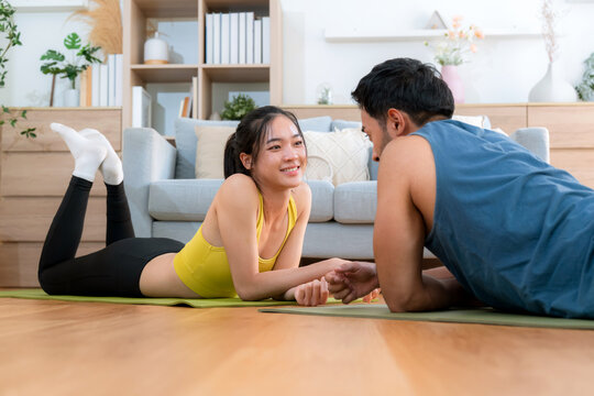 Young asian couple practicing workout with plank while high-five in living room at home, man and woman training exercise for challenge together, motivation and strength of muscle for health. - Powered by Adobe