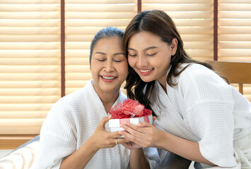 Mother and daughter enjoy a joyful moment together with a special gift during a relaxing spa day at home