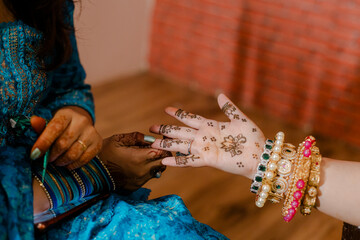 Detailed henna designs being applied to a hand adorned with jewelry, showcasing cultural traditions...