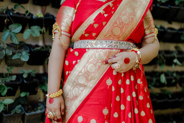 Elegant woman adorned in traditional Indian sari and jewelry. The vibrant red fabric, intricate...