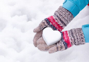 Hands in knitted mittens with heart shaped snow. Winters Day. Valentine's Day
