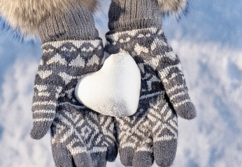 Hands in knitted mittens with heart shaped snow. Winters Day. Valentine's Day