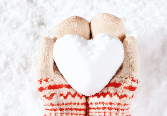 Hands in knitted mittens with heart shaped snow. Winters Day. Valentine's Day