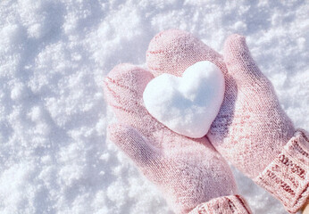 Hands in knitted mittens with heart shaped snow. Winters Day. Valentine's Day
