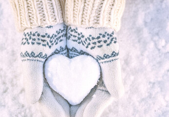 Hands in knitted mittens with heart shaped snow. Winters Day. Valentine's Day