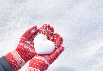 Hands in knitted mittens with heart shaped snow. Winters Day. Valentine's Day