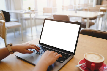 A person's hands typing on a laptop with a blank white screen in a bright, modern cafe. A versatile mockup for business or creative work.