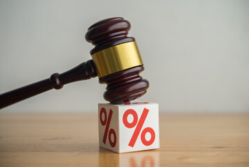 Judge hammer gavel hit on interest rate (percent sign) on table with white wall background. Law on...