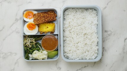 rice, egg and vegetables in lunch boxes with food ready to go for work or school, bento