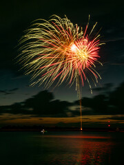 fireworks bursting over the river at dusk