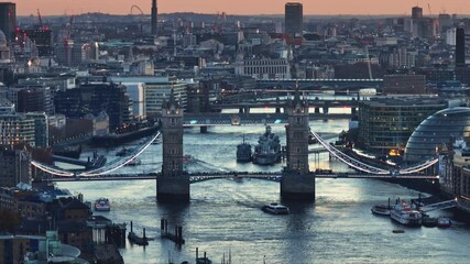 Aerial view of Tower Bridge and HMS Belfast warship on River Thames at sunset, with London skyline cityscape in background, offering a captivating urban landscape. Travel to UK. Drone flight footage - Powered by Adobe