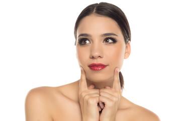 Studio shot on white background with thoughtful woman touching face and looking up.