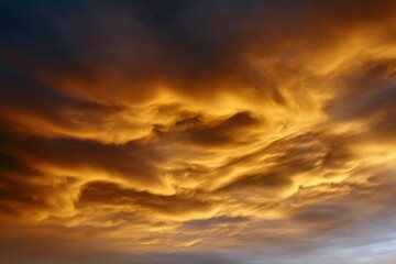 Fototapeta premium Fiery orange clouds in dramatic sky at sunset