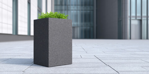 A tall, rectangular stone planter with green plants is placed on a tiled surface in front of a modern glass building. Contemporary urban design