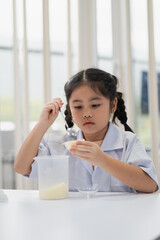 Young Girl in Lab Coat Conducting Science Experiment with Cream in Laboratory Setting, Focused on Science Education and Learning Process