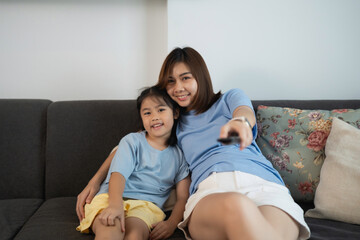 Mother and Daughter Bonding Time on Couch Watching Television Together in Comfortable Living Room Setting with Soft Natural Light