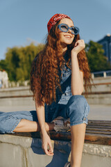 lifestyle woman in modern boho-western denim street style wearing sunglasses and a red bandana with...