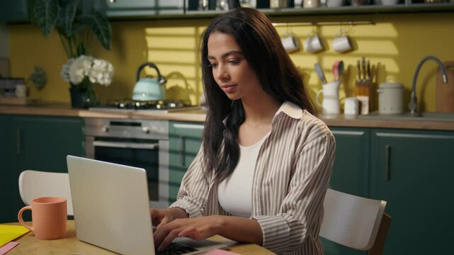 Woman teen girl Latina Hispanic ethnic student studying at home kitchen browsing laptop internet search shopping delivery female teenage gen z freelancer businesswoman using computer pc online working