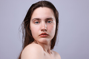Portrait of woman with natural skin complexion on grey background, closeup