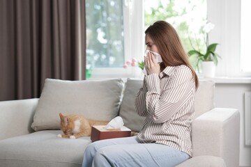 Woman suffering from allergy with her cat on sofa at home
