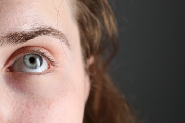 Woman with beautiful eyes on grey background, closeup. Space for text