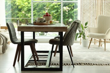 Wooden table, chairs, armchair and decor in dining room. Interior design