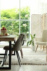 Wooden table, chairs, armchair and decor in dining room. Interior design